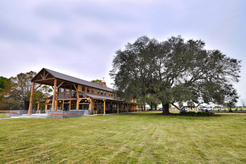 Open-air barn pavilion beside a large oak tree at Cottonwood Ranch